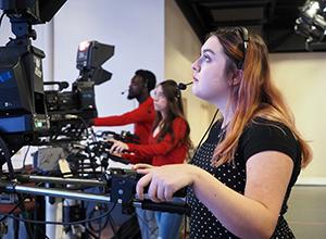 传媒专业的学生在校园新闻室里运行摄像机.