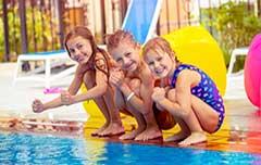三个孩子在泳池边参加游泳派对.