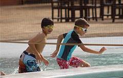 两个男孩戴着护目镜在泳池里跑.